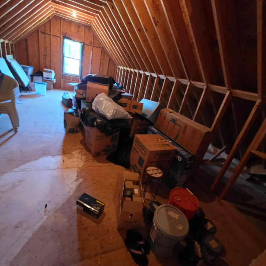 Attic filled with broken furniture and debris before cleanout