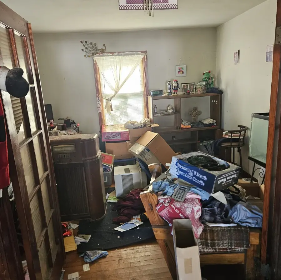Bedroom filled with furniture, boxes and belongings before estate cleanout