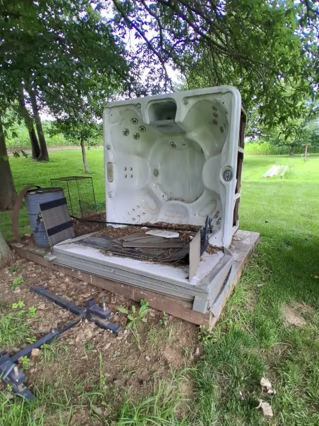 Damaged hot tub on a raised outdoor platform before removal