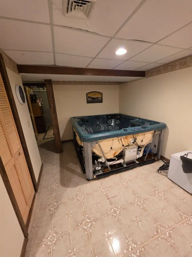 Large hot tub inside a basement room before removal