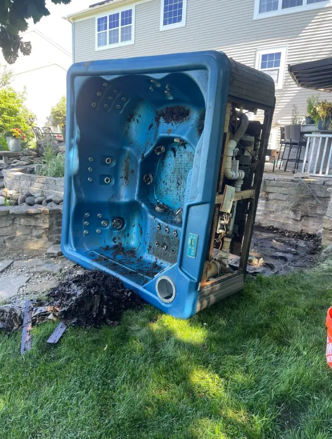 Blue backyard hot tub beside a stone patio before removal