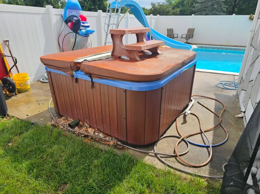 Hot tub beside a residential swimming pool before removal
