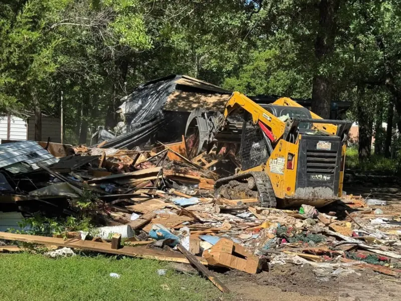 Compact loader clearing lumber and debris from a small demolition project