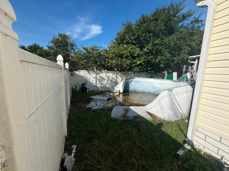 Damaged above-ground pool in a narrow side yard before removal