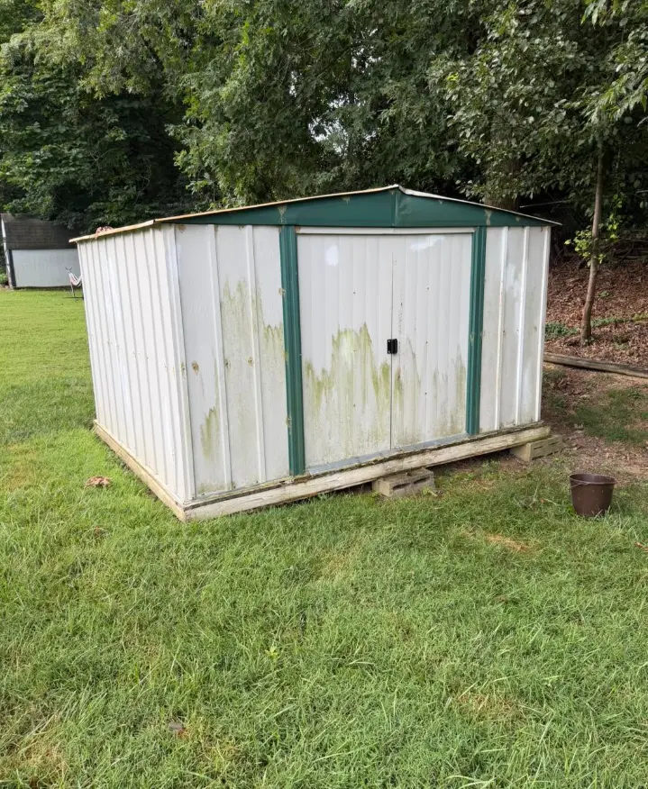 White and green metal storage shed before removal