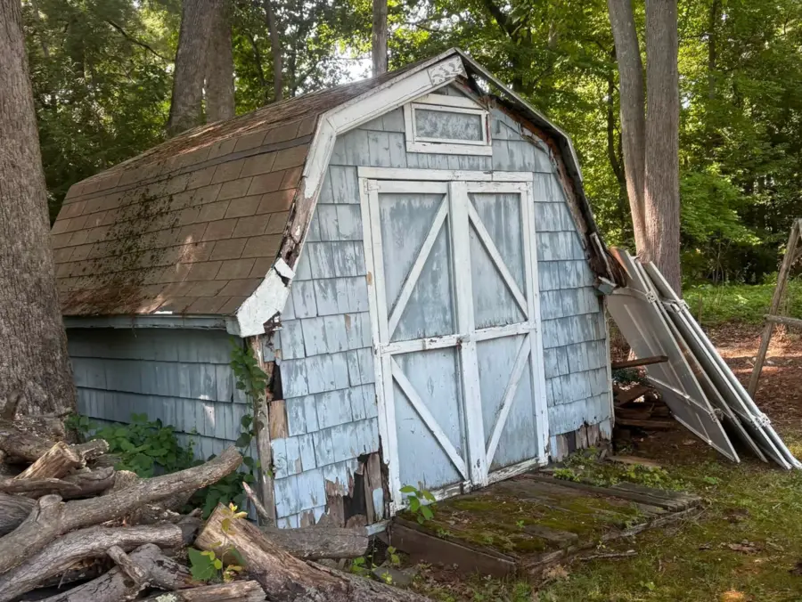 Deteriorated barn-style wooden shed before removal