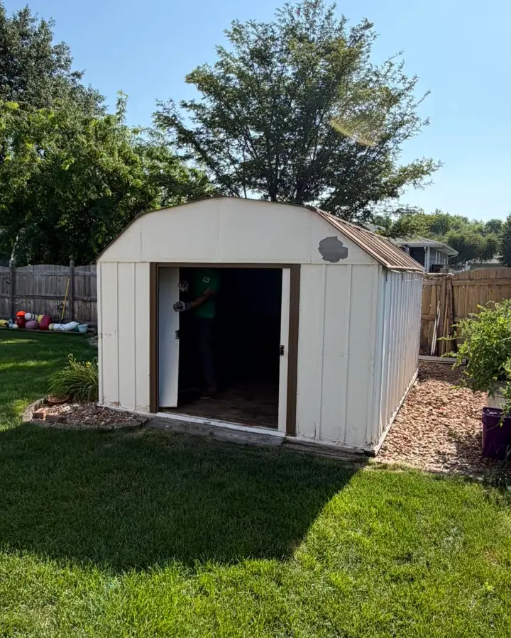 Large white metal backyard shed before removal