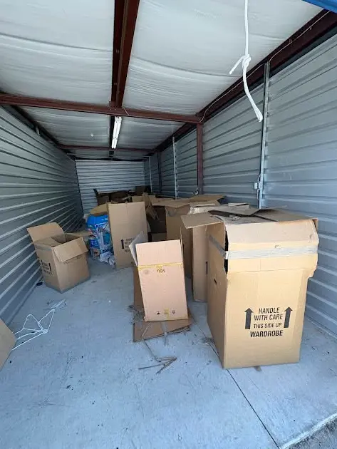 Storage unit with cardboard boxes and household items before cleanout