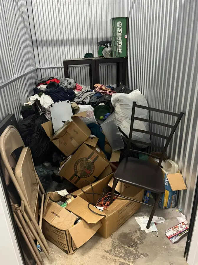 Storage unit filled with clothing and boxes before cleanout