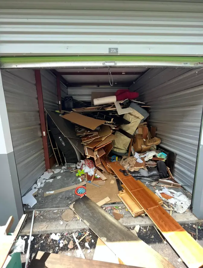Storage unit filled with broken furniture and debris before cleanout